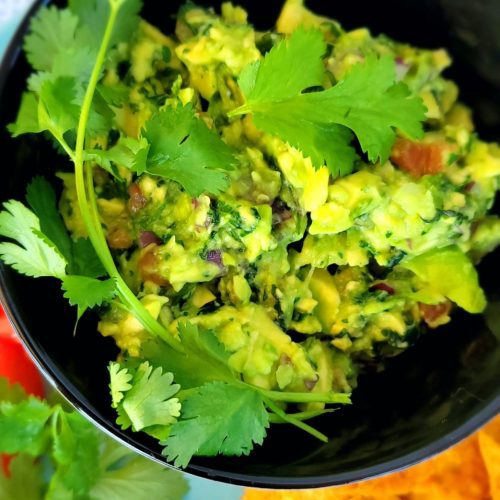 Guacamole in a bowl garnished with Cilantro